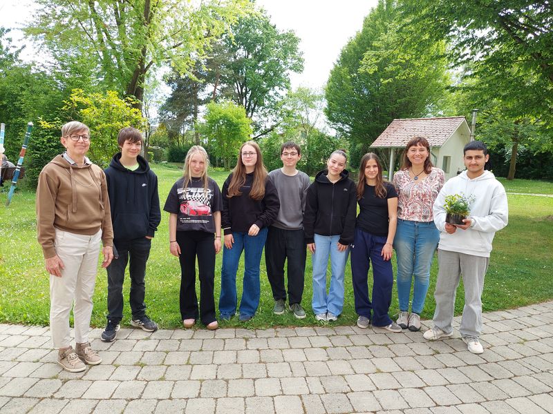 Schülerinnen und Schüler mit Mitarbeitenden im Garten des Konrad-Manopp-Stifts