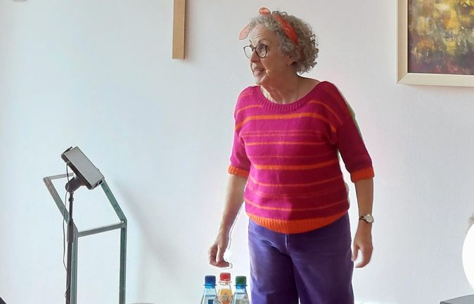 Frau spricht vor sitzenden Senioren beim Sommerfest im Konrad-Manopp-Stift