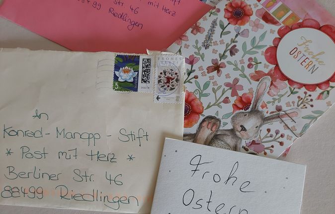 Mehrere Briefe und Osterkarten mit rosa Umschlag und Herzstempel