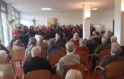 Kirchenchor singt bei Maiandacht vor sitzender Gemeinde im Gemeindesaal