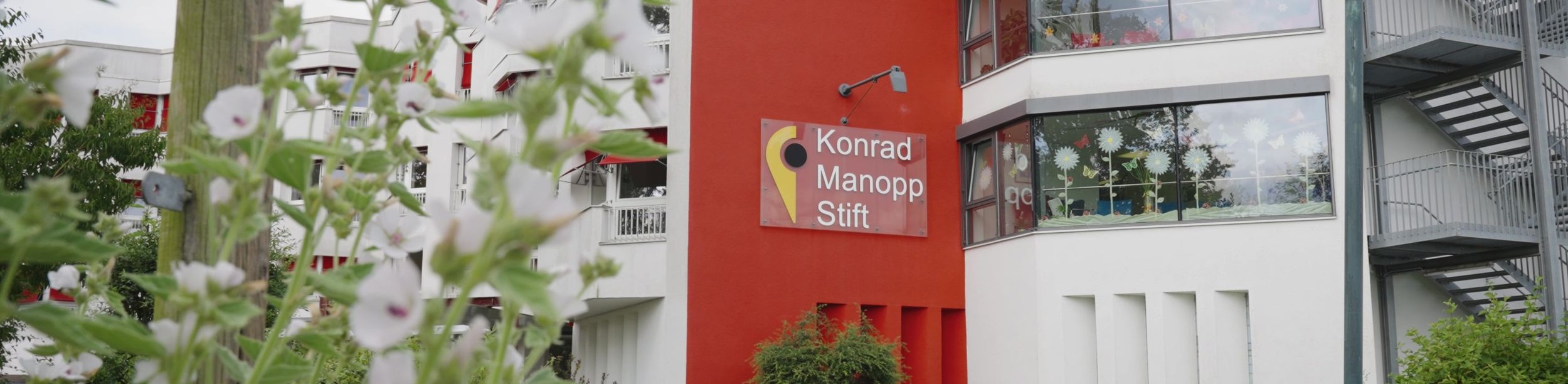Rotes und weißes Gebäude mit Schild Konrad Manopp Stift und dekorierten Fenstern