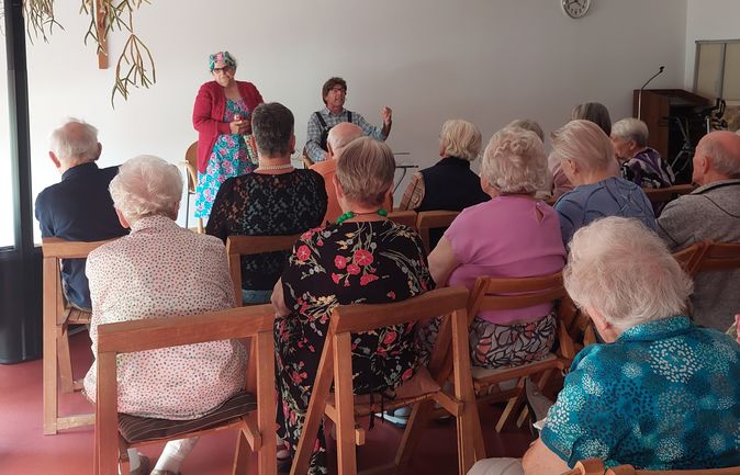 Zwei Darsteller in Kostümen vor sitzendem Seniorenpublikum