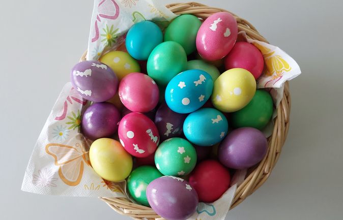 Korb mit bunten Ostereiern und weißen Hasenmotiven