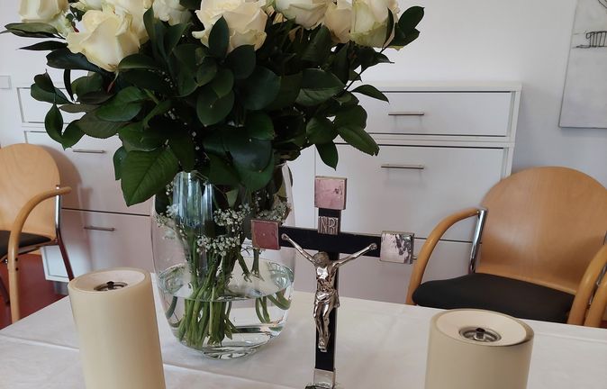 Tisch mit weißen Rosen, Kreuz und Kerzen beim Gedenkgottesdienst