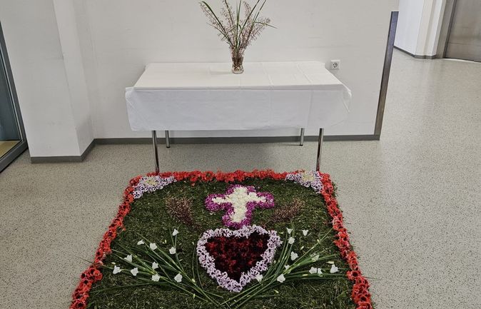 Blumenteppich mit Kreuz Herz und Fisch vor Altar
