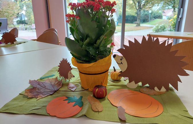 Herbstliche Tischdekoration mit Topfpflanze, Igel‑Bastelmotiven und Papierkürbissen