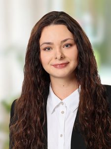 Porträt einer lächelnden Frau mit langen braunen Haaren im Blazer