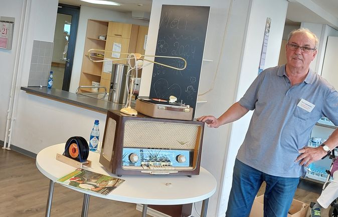 Mann präsentiert altes Radio und Plattenspieler im Veranstaltungsraum