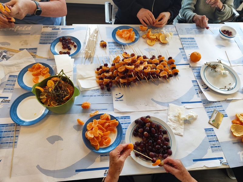 Fruchtspieße und Hände, die sie zubereiten