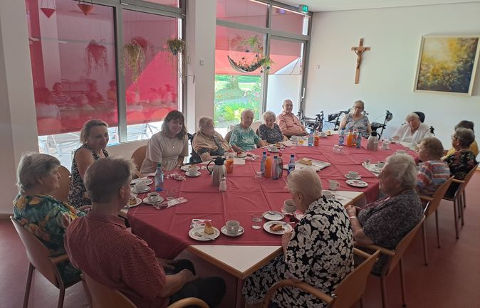 Seniorinnen und Senioren bei gemeinsamer Kaffeetafel mit Besuchern