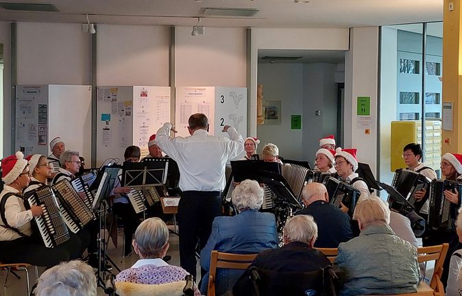 Akkordeonorchester Tastenzauber in Weihnachtsmützen vor Seniorenpublikum