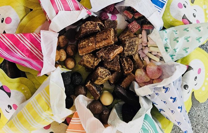 Bunte Papiertüten mit Süßigkeiten auf gelben lachenden Unterlagen