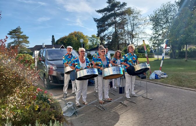 Steelband Kolibris spielt auf Stahlkesseln in farbenfrohen Hemden