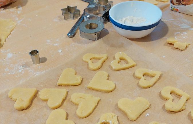Weihnachtliche Plätzchen mit Herz- und Sternausstechern auf Backpapier