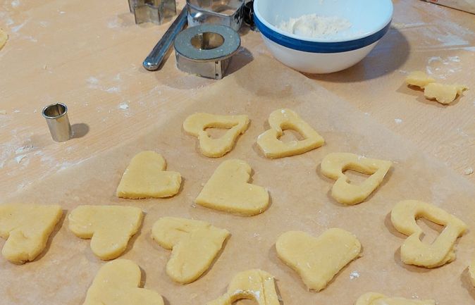 Weihnachtliche Plätzchen mit Herz- und Sternausstechern auf Backpapier
