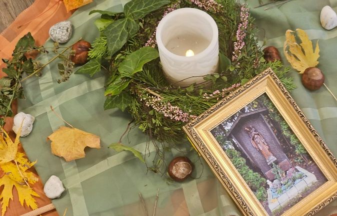 Andachtsaltar zu Allerheiligen mit Kerze Kranz und gerahmtem religiösem Bild