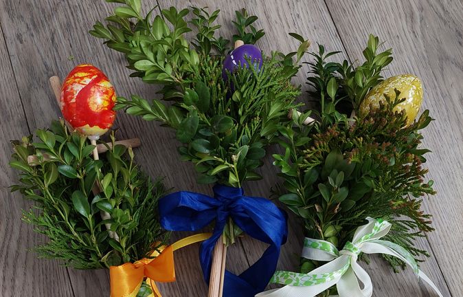 Drei Handpalmen aus Buchs und Thujazweigen mit bunten Ostereiern und Schleifen