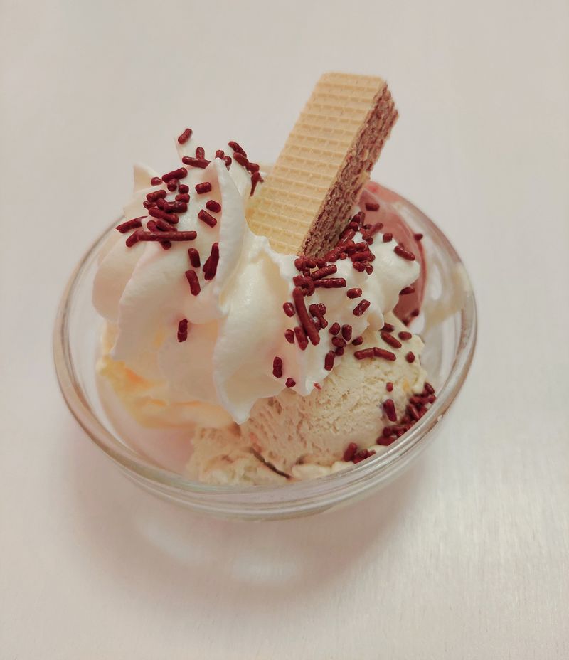 Eisbecher mit hellem Eis, Sahne, Schokostreuseln und Waffel
