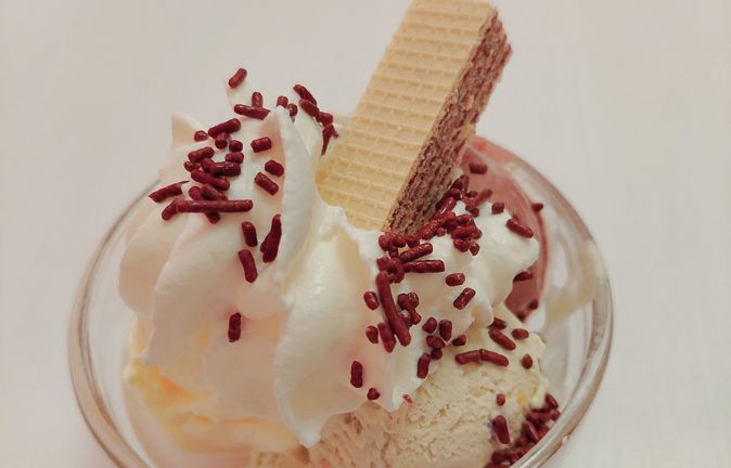 Eisbecher mit hellem Eis, Sahne, Schokostreuseln und Waffel