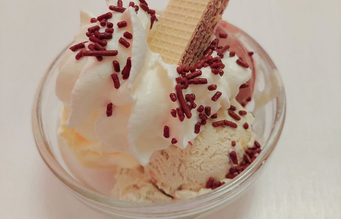 Eisbecher mit hellem Eis, Sahne, Schokostreuseln und Waffel