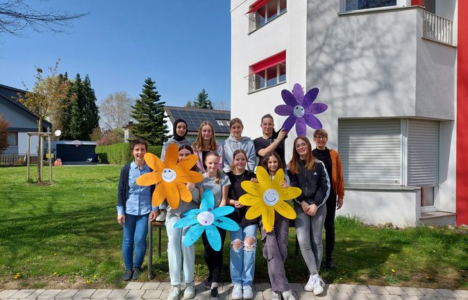 Jugendliche und Betreuende vor Konrad-Manopp-Stift mit bunten Papierblumen