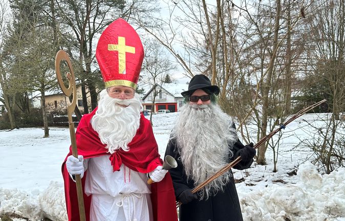 Verkleideter Nikolaus mit Bischofsmütze und Begleiter mit Rute im Schnee