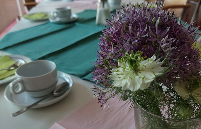 Gedeckter Frühstückstisch mit Kaffeetassen und Blumenstrauß