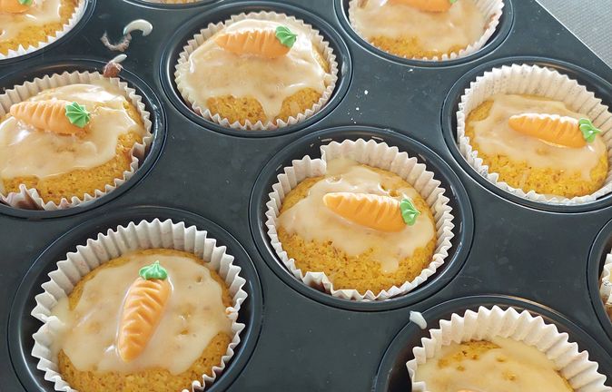 Muffins mit Glasur und kleinen orange-grünen Karotten-Dekoren