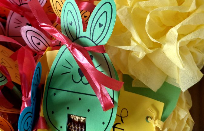 Bunte Papierosterhasen mit roten Schleifen und gelben Blumen für Bewohnerinnen und Bewohner